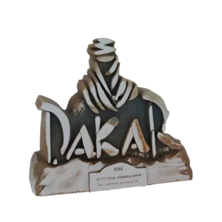 3D-модель трофея ралли Дакар 1996 года с логотипом 'DAKAR' и фигуркой пустынного гонщика.