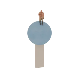 3D модель миниатюрного человечка в бежевом комбинезоне, стоящего на светло-синей сфере, которая покоится на бежевом прямоугол