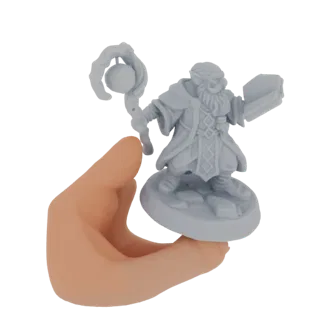 3D-модель серой миниатюры гнома-волшебника с посохом и книгой, показанная в руке человека.