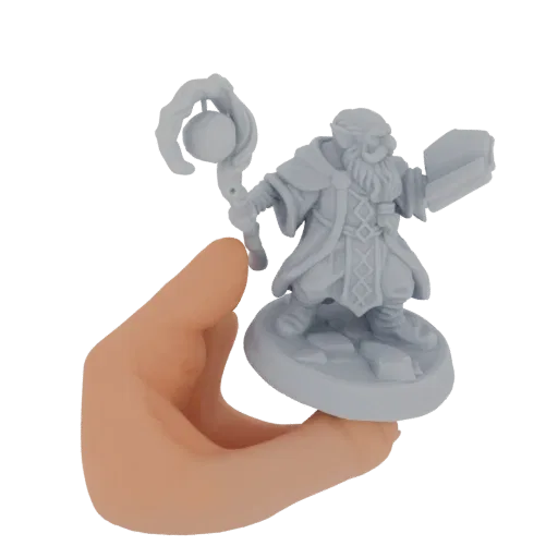 3D-модель серой миниатюры гнома-волшебника с посохом и книгой, показанная в руке человека.