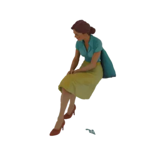 3D модель женщины в бирюзовой блузке и желтой юбке, сидящей со сложенными на коленях руками и опущенным взглядом.