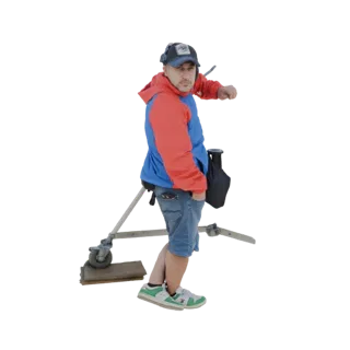 3D-модель мужчины в красно-синей куртке рядом с тележкой для камеры, рука в кармане.